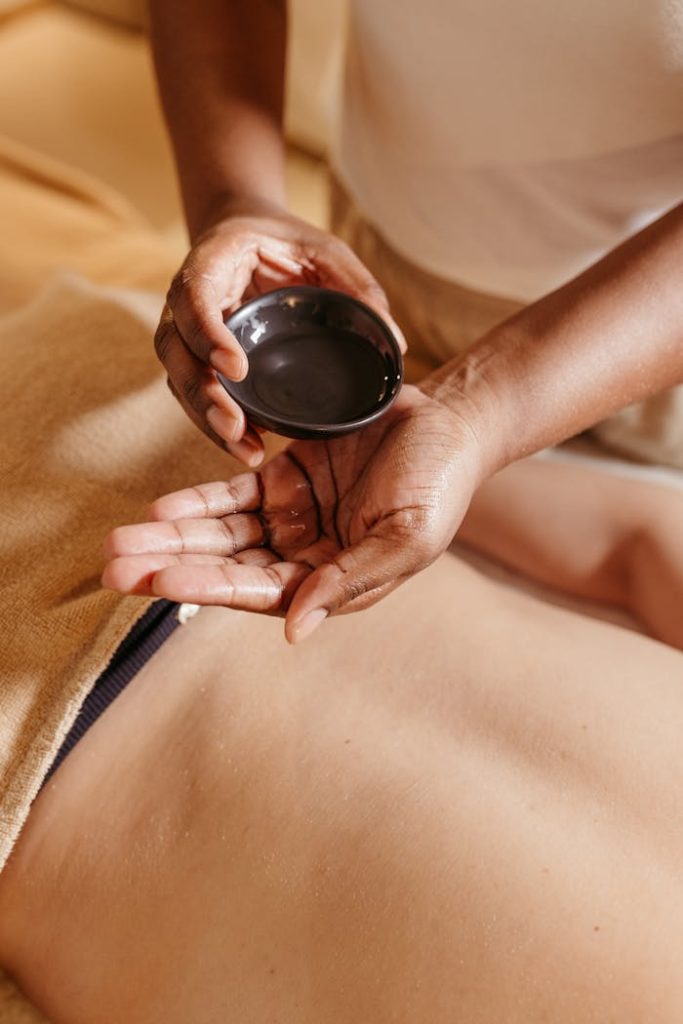 pexels-photo-19641816 Hands applying massage oil on a client's back in a spa setting for relaxation and rejuvenation.