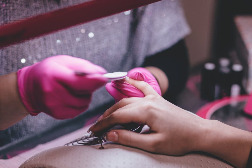 pexels-photo-332046 Close-up of a professional manicure session with pink gloves and a nail file in an indoor salon.