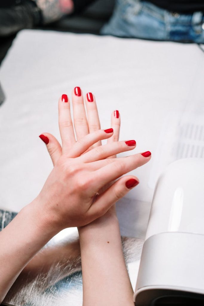 pexels-photo-3997381 Close-up of red manicured nails during a salon session with nail tools.
