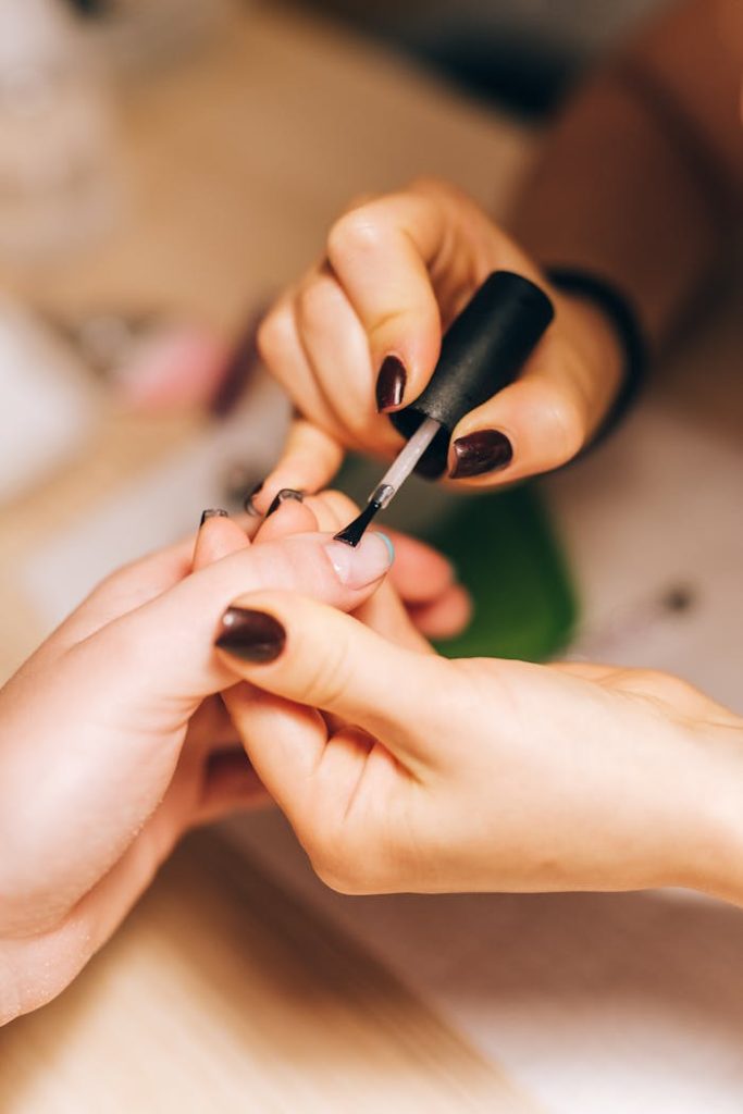 pexels-photo-4677845 Close-up of a manicurist applying nail polish during a professional manicure session.
