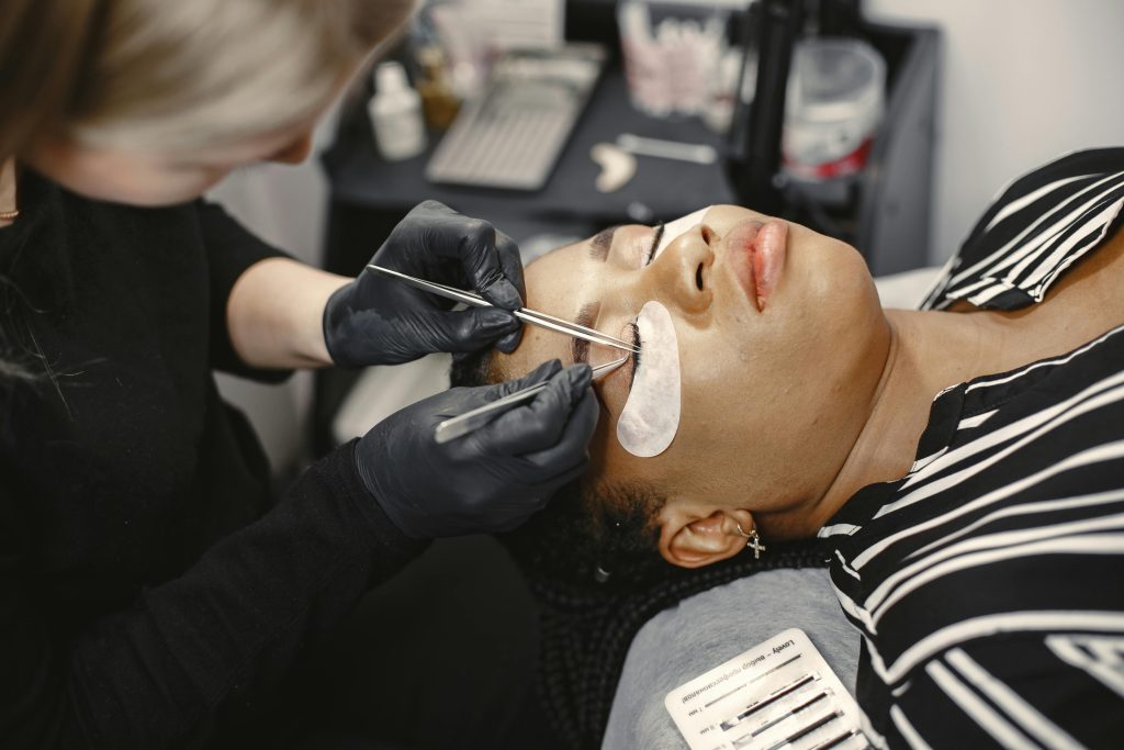 pexels-photo-7446922-7446922 Beauty treatment with a technician applying eyelash extensions to a client in a salon setting.