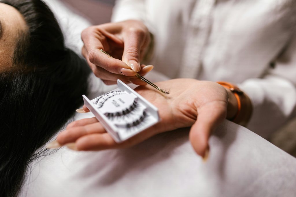 pexels-photo-7755523-7755523 Close-up of an eyelash extension application using tweezers, featuring a beautician's hands.