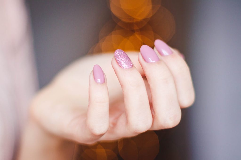pexels-photo-939836 A close-up of a woman's hand displaying a stylish pink glitter manicure, highlighting nail art details.